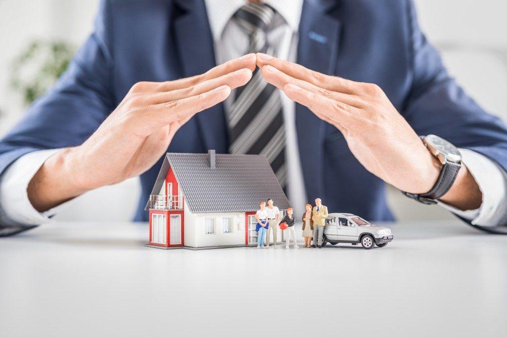 Business man with hands covering home figure