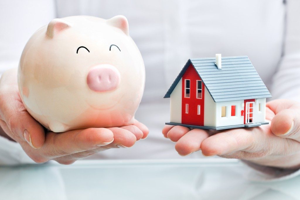 Man holding a piggy bank and a house model
