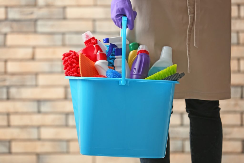 person holding a container full of cleaning tools