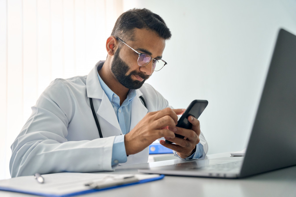 male doctor in his office using his phone