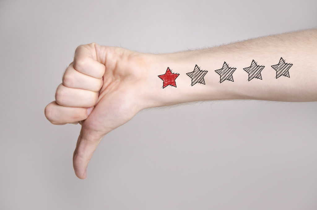 a hand doing a thumbs down sign with a 1-star review drawing in its hand